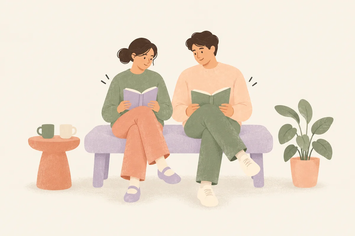 A couple reading separate books on a lavender bench, with two mugs on a small table and a potted plant beside them.